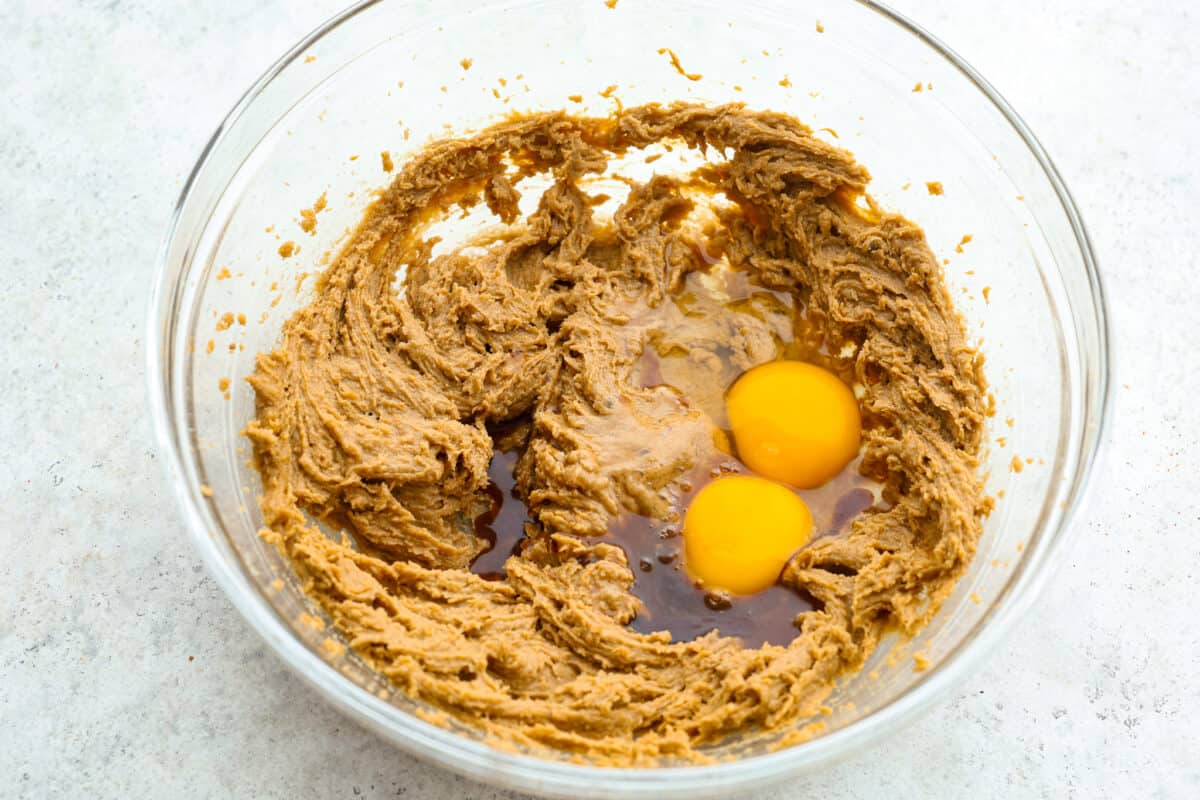 Monster cookies are slightly crisp on the outside, and soft and chewy in the center. They are loaded with peanut butter, oats, M&M candies, AND chocolate chips! Big monster cookies win every time! Process shot of eggs and vanilla added to the bowl.