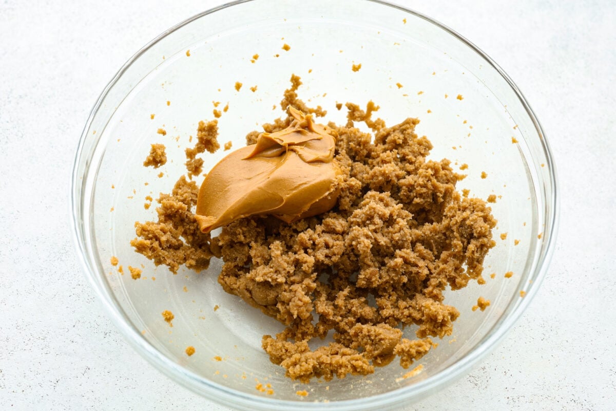 Monster cookies are slightly crisp on the outside, and soft and chewy in the center. They are loaded with peanut butter, oats, M&M candies, AND chocolate chips! Big monster cookies win every time! Process shot of peanut butter added to the creamed butter and sugars.