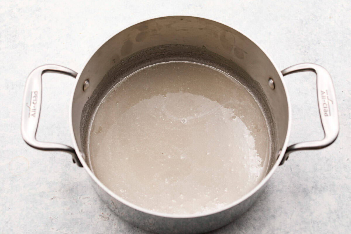 Treat yourself to this luxurious and refreshing Swedish Cream, a classic dessert that's easy to make. With a few simple ingredients and some chill time, you'll have a delightful treat topped with fresh berries and mint. Overhead shot of a silver pot with water, gelatin and sugar in it sitting on the counter.
