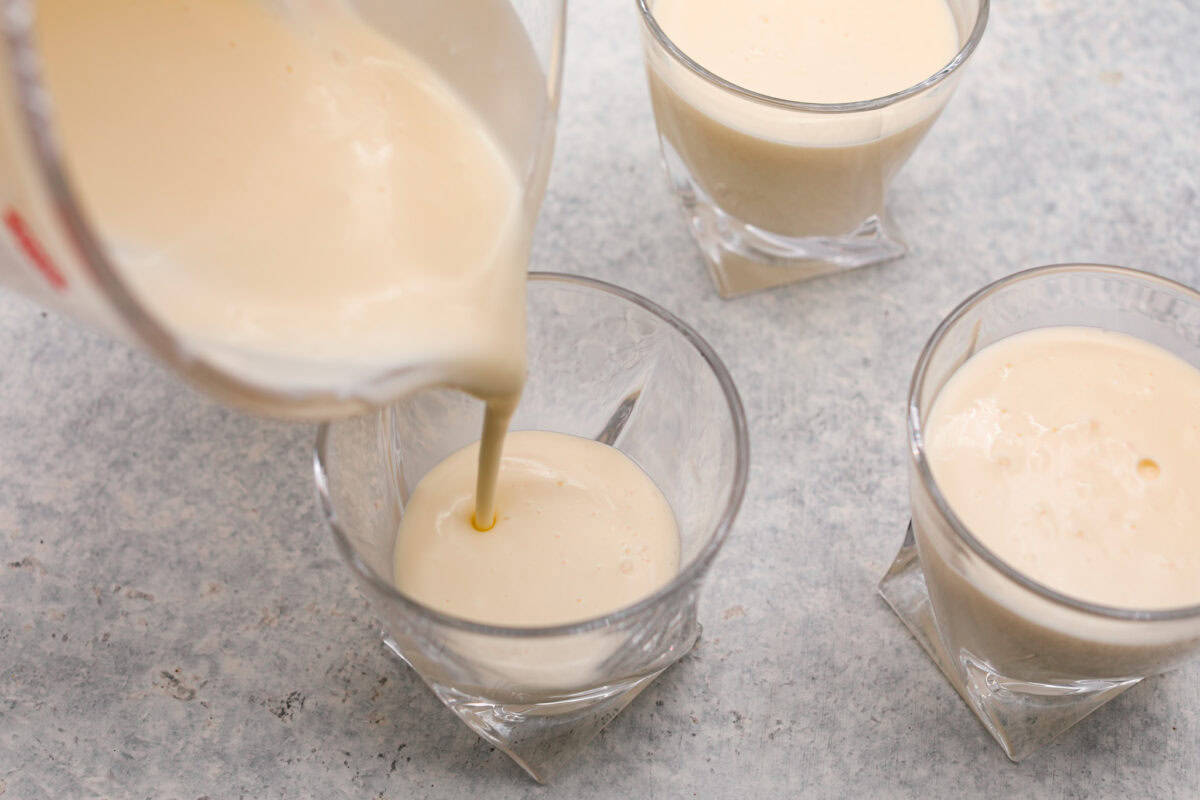 Treat yourself to this luxurious and refreshing Swedish Cream, a classic dessert that's easy to make. With a few simple ingredients and some chill time, you'll have a delightful treat topped with fresh berries and mint. Overhead shot of individual cups of cream mixture, with one having cream mixture being poured into it.