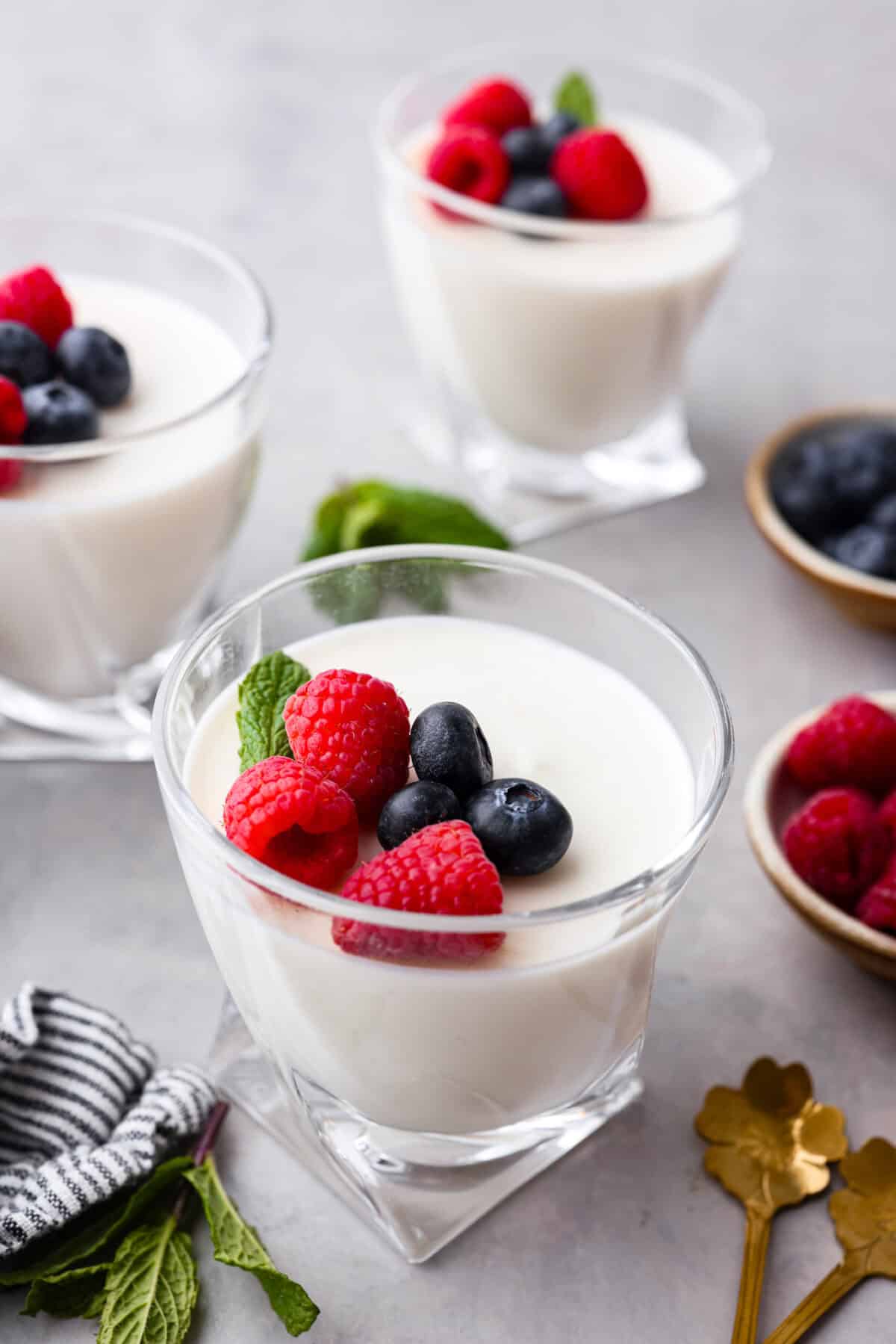Treat yourself to this luxurious and refreshing Swedish Cream, a classic dessert that's easy to make. With a few simple ingredients and some chill time, you'll have a delightful treat topped with fresh berries and mint. Angle shot of a glass cup with Swedish cream with raspberries, blueberries and a sprig of mint on top.