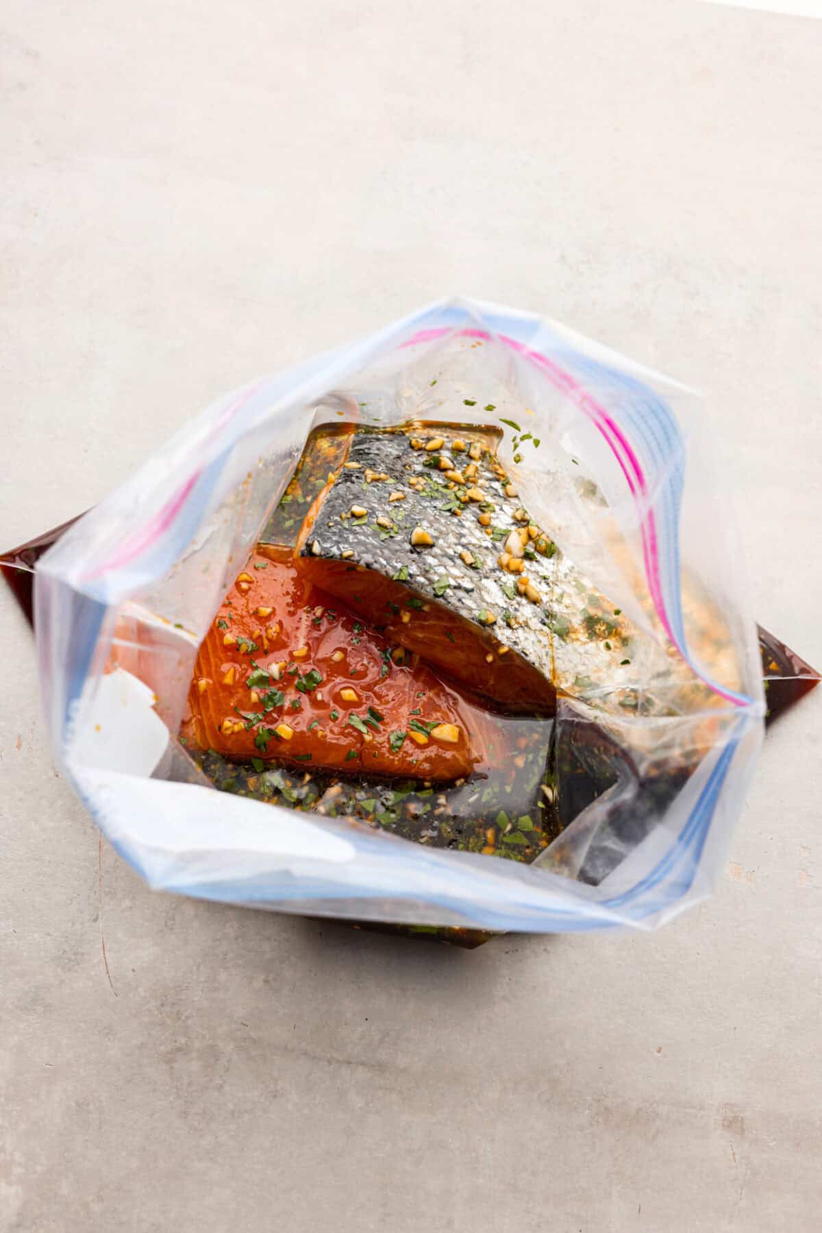 A good salmon marinade is the best way to achieve a seafood meal that's incredibly flavorful with tender, juicy fish! The top view of salmon filets in marinade in a ziplock bag.