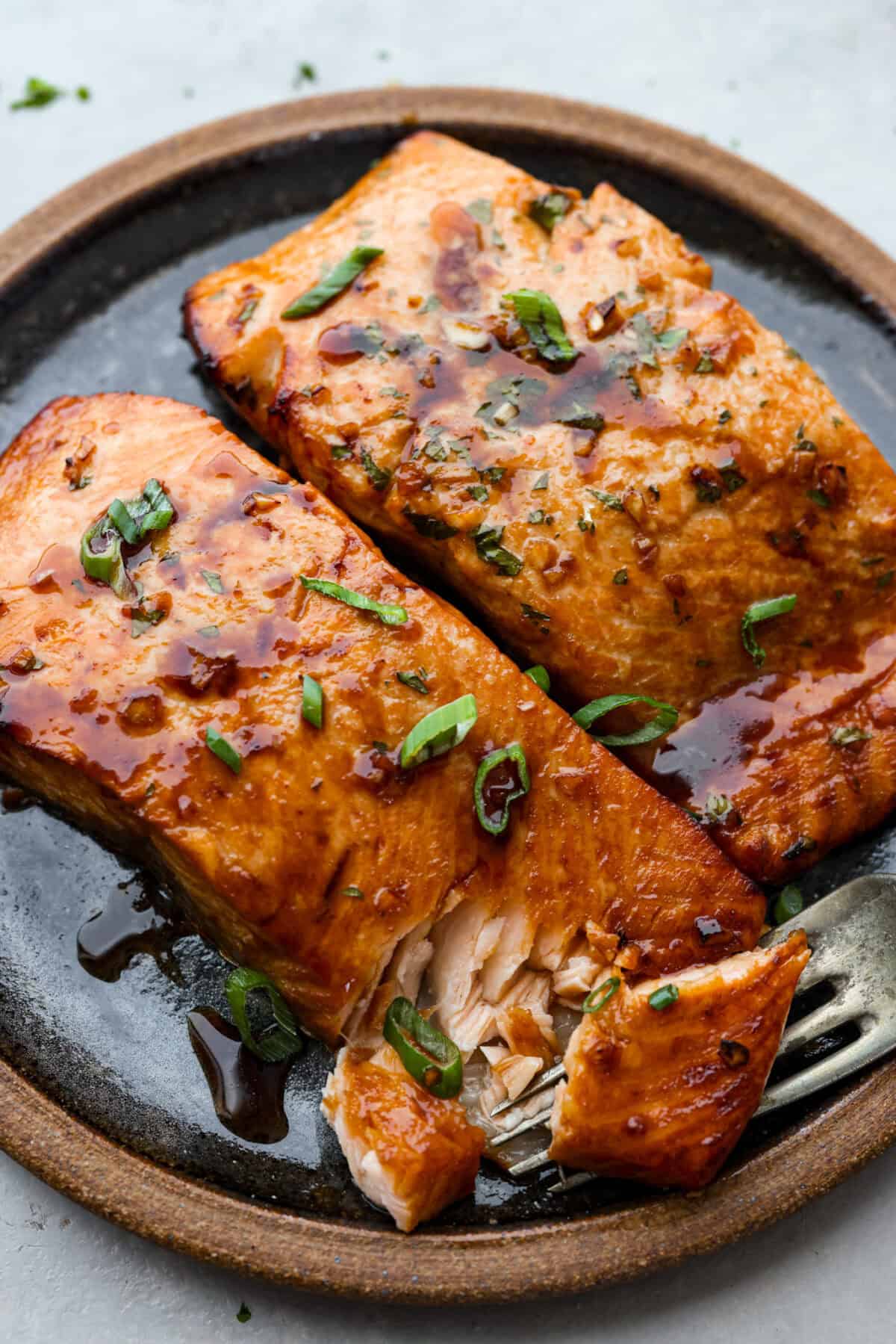A good salmon marinade is the best way to achieve a seafood meal that's incredibly flavorful with tender, juicy fish! Cooked salmon filets on a plate garnished with green onions.