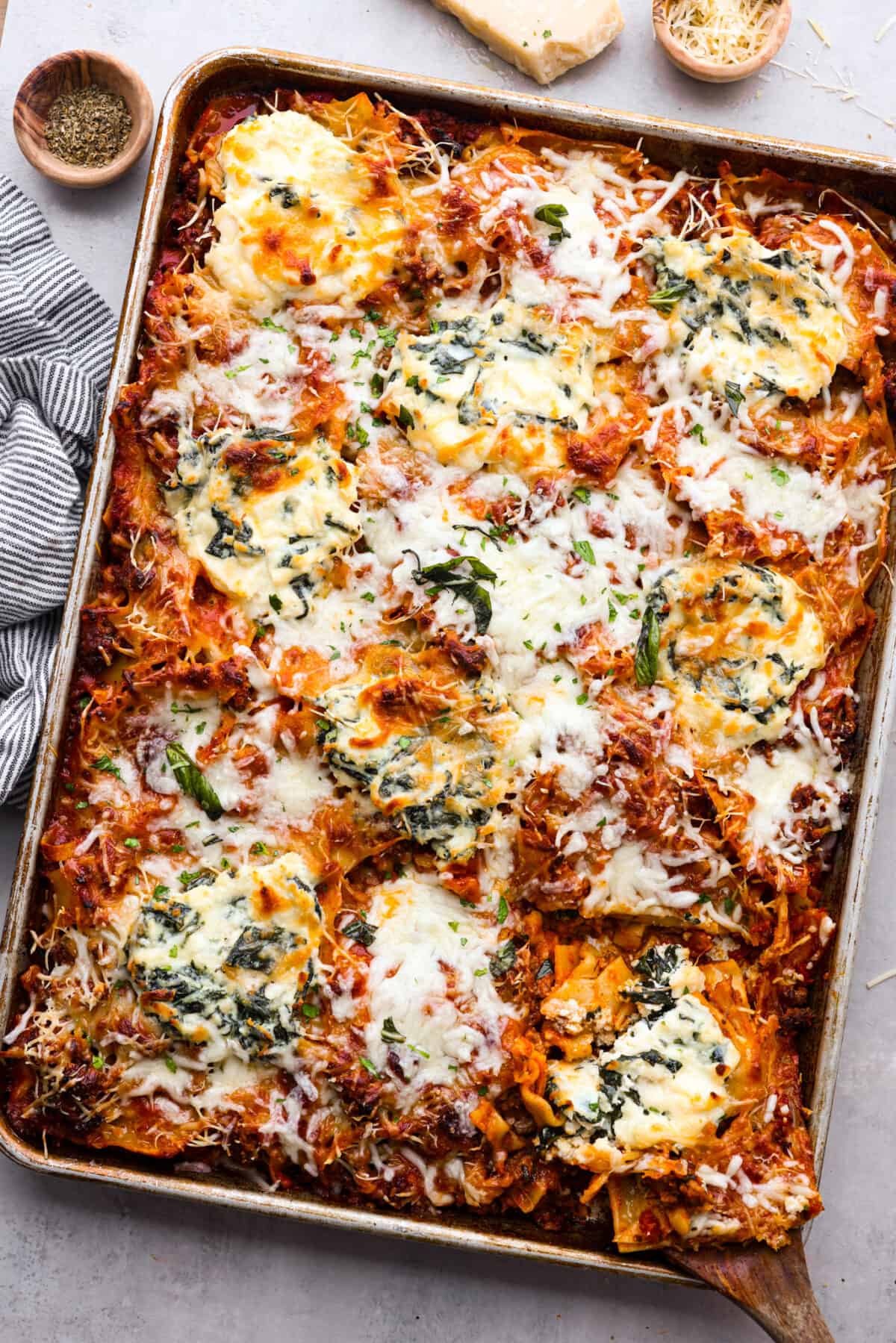 This super easy sheet pan lasagna is stacked with sautรฉedย ground beef and Italianย sausage that are cooked together, marinaraย sauce,ย creamy spinach ricotta, lasagna noodles and melty cheese for an amazingย Italian dinner. The top view of sheet pan lasagna.