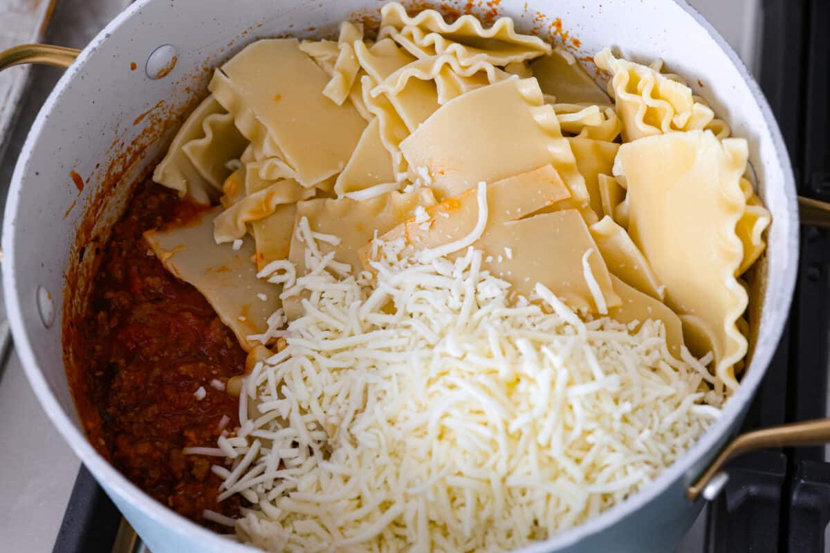 This super easy sheet pan lasagna is stacked with sautรฉedย ground beef and Italianย sausage that are cooked together, marinaraย sauce,ย creamy spinach ricotta, lasagna noodles and melty cheese for an amazingย Italian dinner. Noodles being added to a pot.