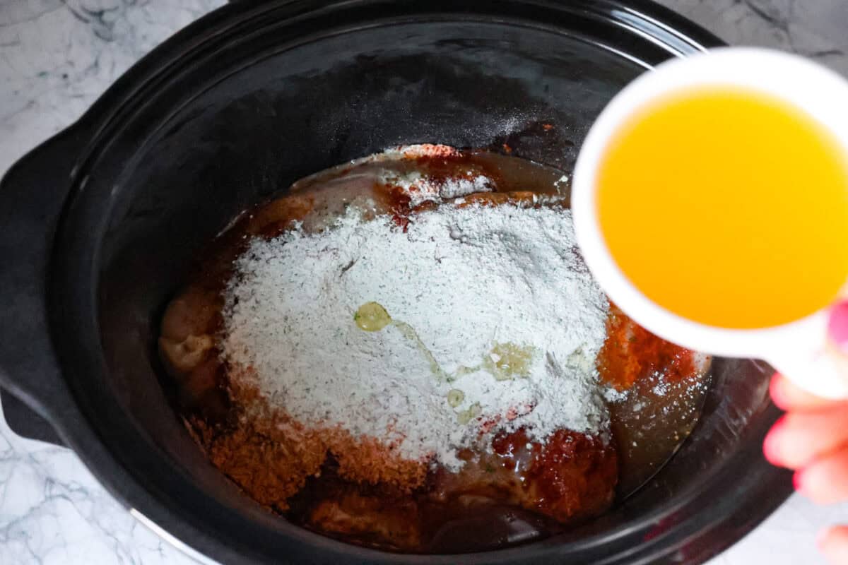 Switch up taco night with these 4-ingredient slow cooker ranch tacos! The chicken shreds perfectly and is packed with flavor. Dinner has never been easier! Second process photo of the chicken broth pouring into the slow cooker.