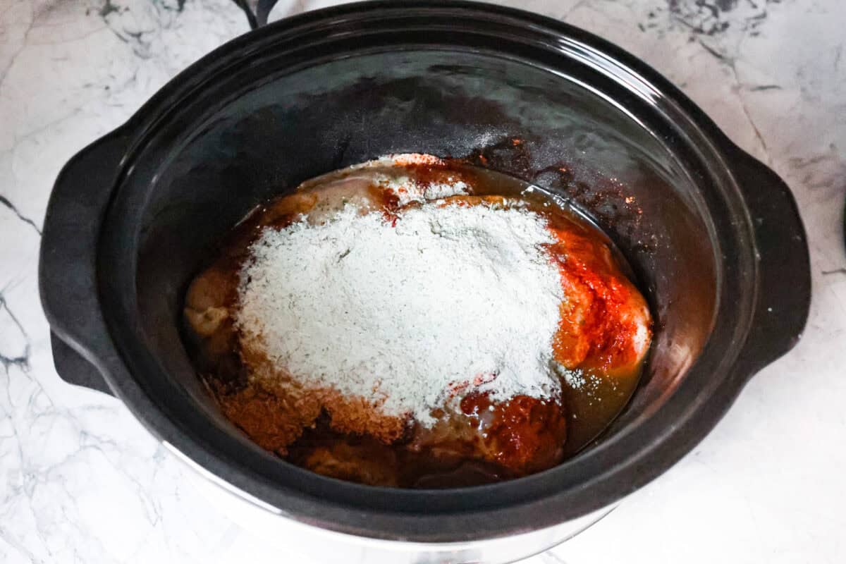 Switch up taco night with these 4-ingredient slow cooker ranch tacos! The chicken shreds perfectly and is packed with flavor. Dinner has never been easier! First process photo of the chicken and seasoning in the slow cooker.