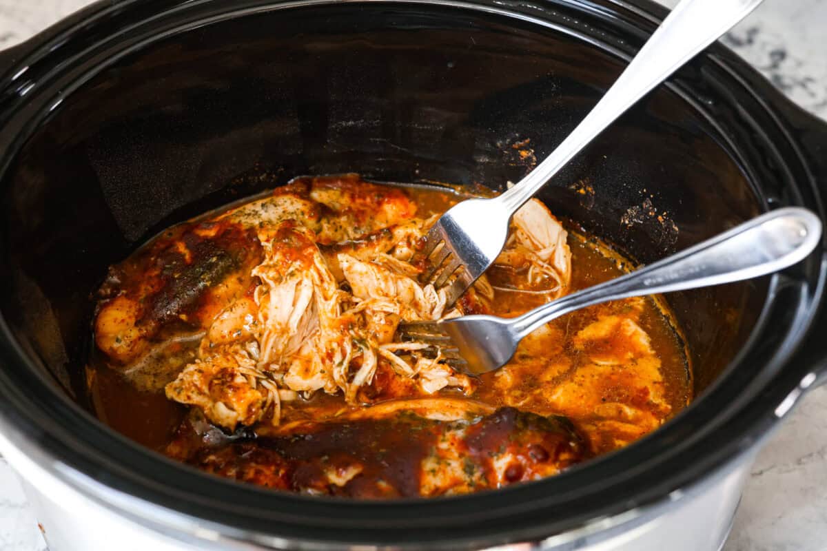 Switch up taco night with these 4-ingredient slow cooker ranch tacos! The chicken shreds perfectly and is packed with flavor. Dinner has never been easier! Third process photo of the chicken shredding.
