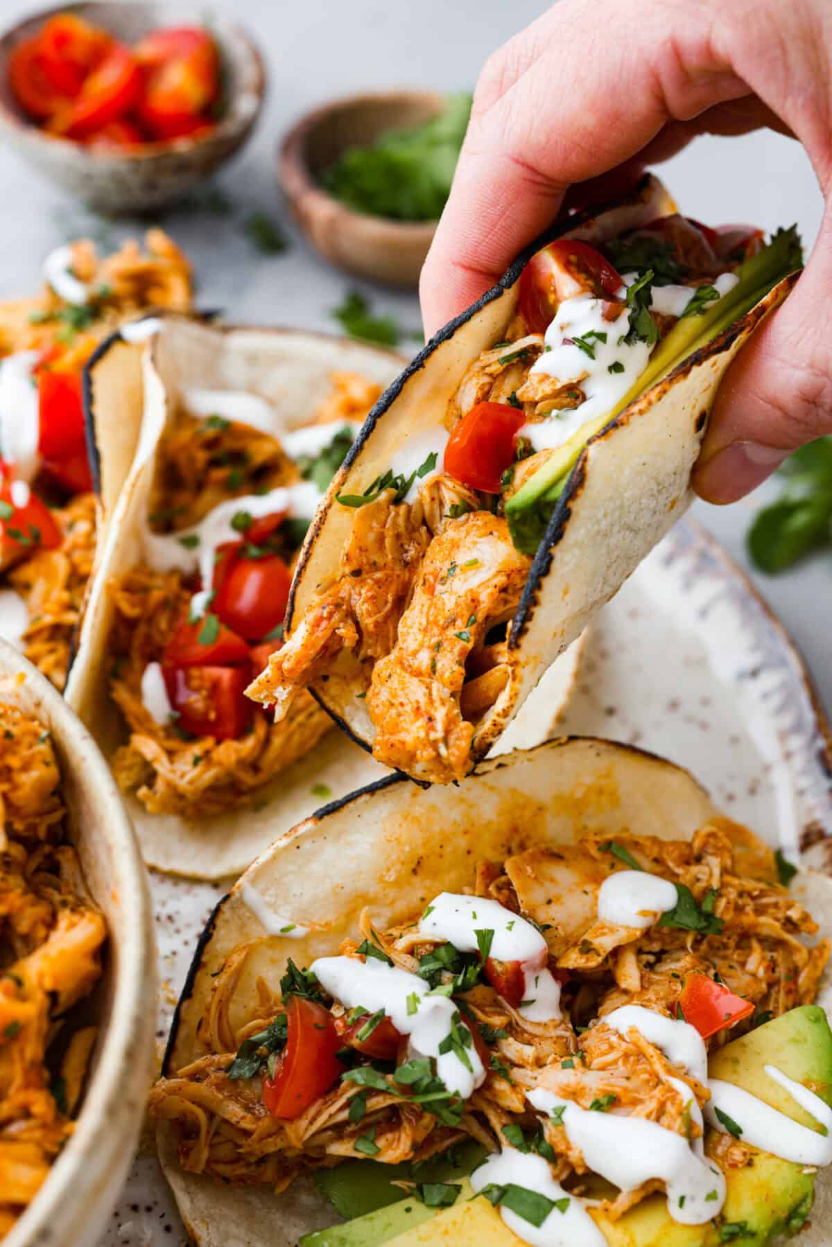 Switch up taco night with these 4-ingredient slow cooker ranch tacos! The chicken shreds perfectly and is packed with flavor. Dinner has never been easier! Close view of a hand holding an assembled taco.