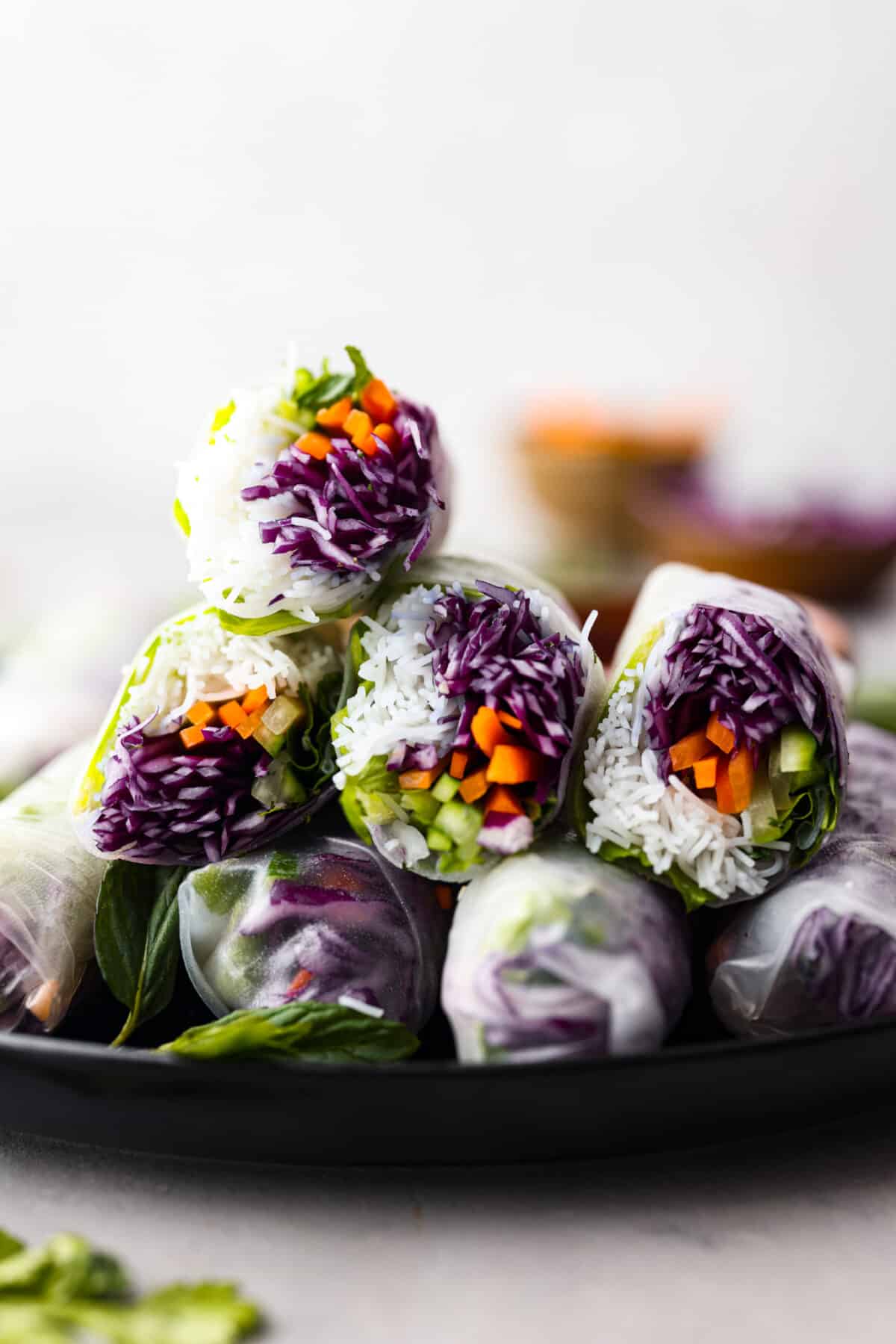 Spring rolls are a delightful, fresh, and vibrant snack that's perfect for any occasion. With ingredients like crisp carrots, refreshing mint, and tender rice vermicelli, these rolls are not only healthy but also bursting with flavor. Stacked spring rolls on a plate.