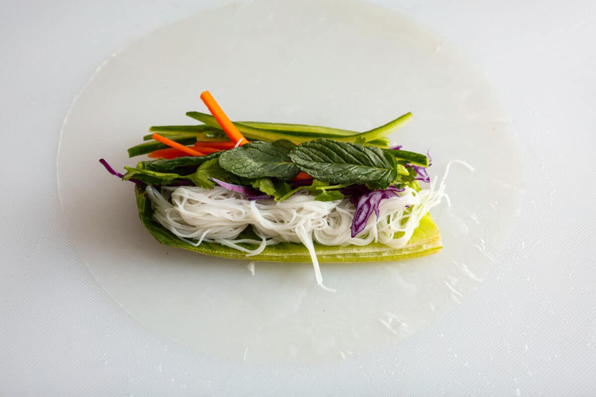 Spring rolls are a delightful, fresh, and vibrant snack that's perfect for any occasion. With ingredients like crisp carrots, refreshing mint, and tender rice vermicelli, these rolls are not only healthy but also bursting with flavor. Ingredients added to the top of the rice paper.