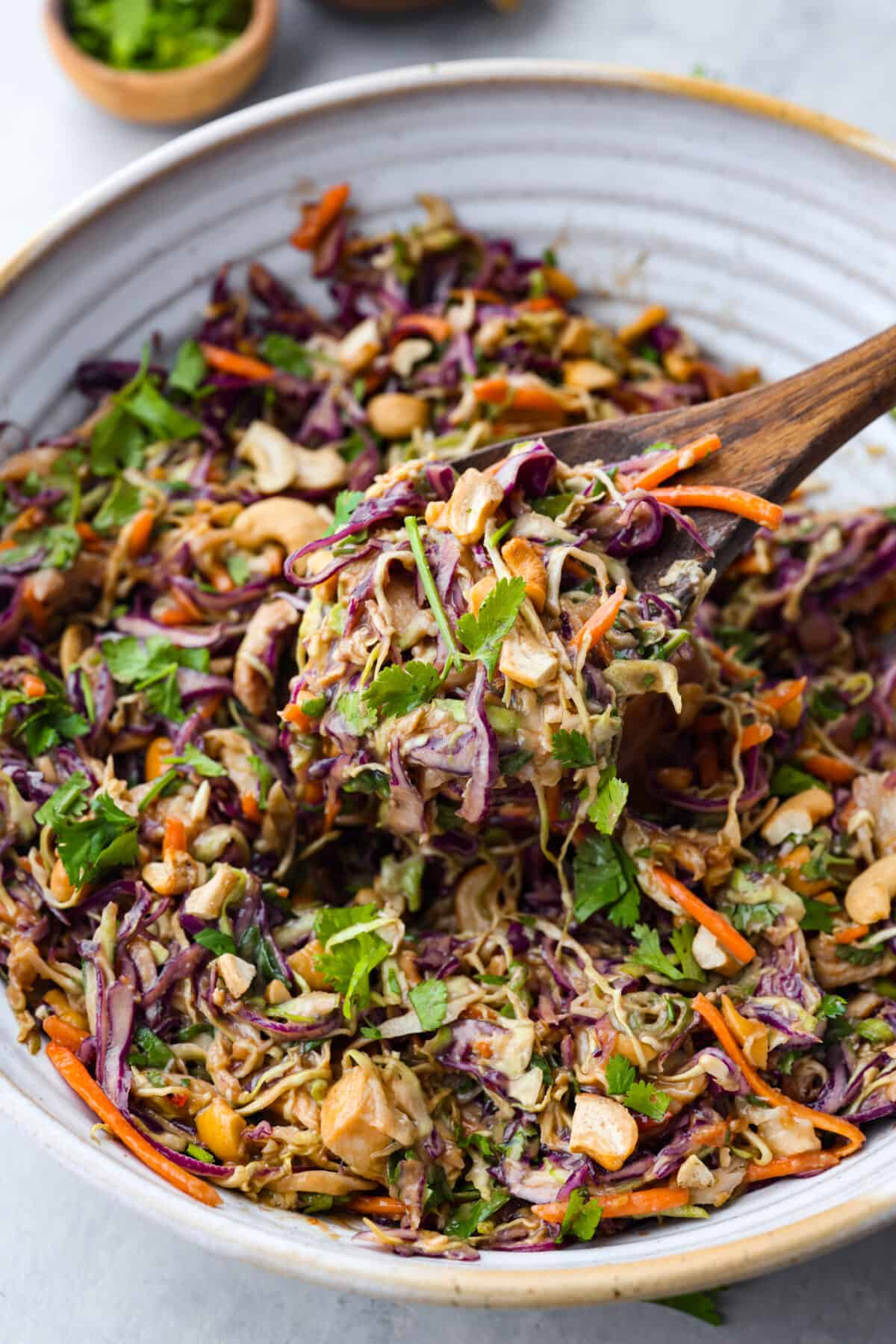 Crunchy and bright, this Thai Chicken Salad with creamy peanut dressing is bursting with flavor, texture and deliciousness! Prep it in under 30 minutes for an easy side dish or a delicious lunch! A close up of the Thai Chicken Salad in a bowl.