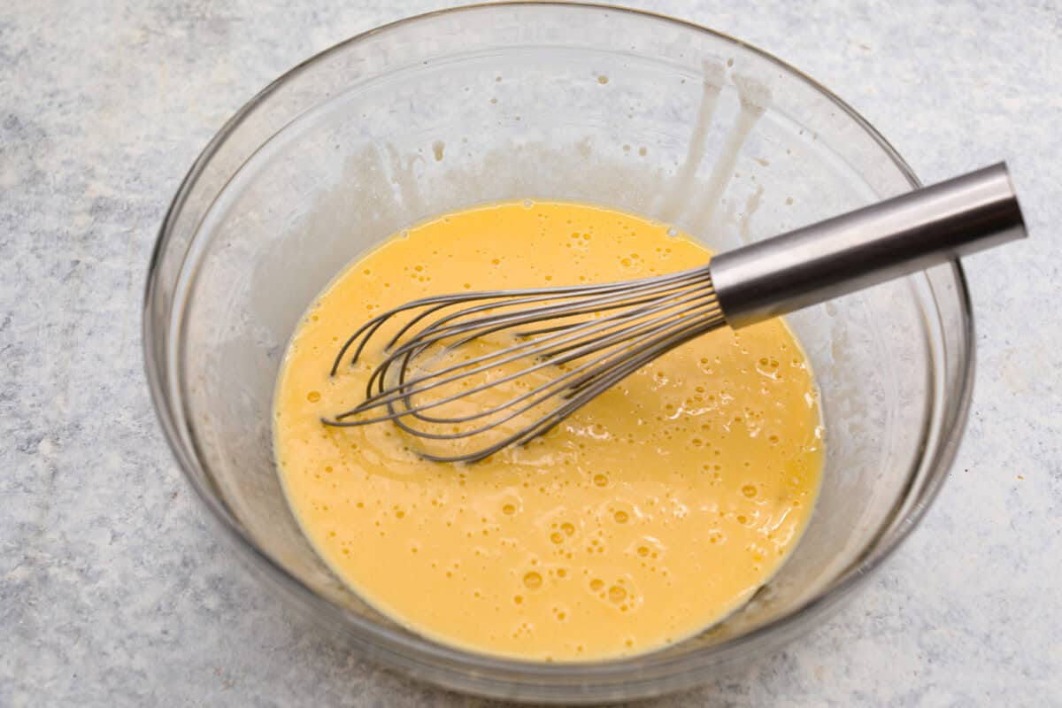 This Twinkie cake is a fun dessert that brings the classic snack cake to life. With its fluffy vanilla sponge and creamy filling, it's sure to be a hit with everyone! Wet ingredients whisked together in a glass bowl.