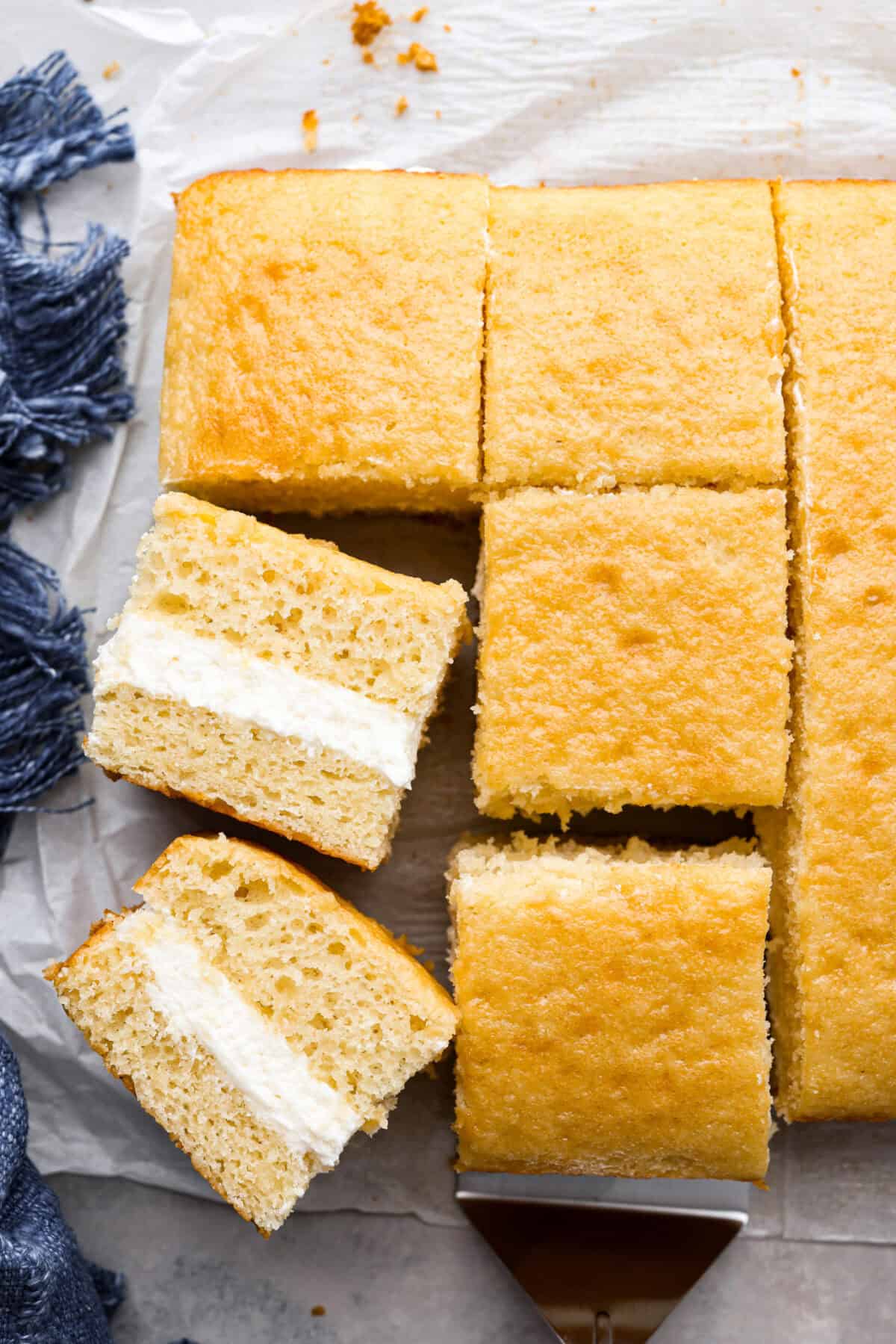 This Twinkie cake is a fun dessert that brings the classic snack cake to life. With its fluffy vanilla sponge and creamy filling, it's sure to be a hit with everyone! Top view of a Twinkie cake with a few pieces on their sides.