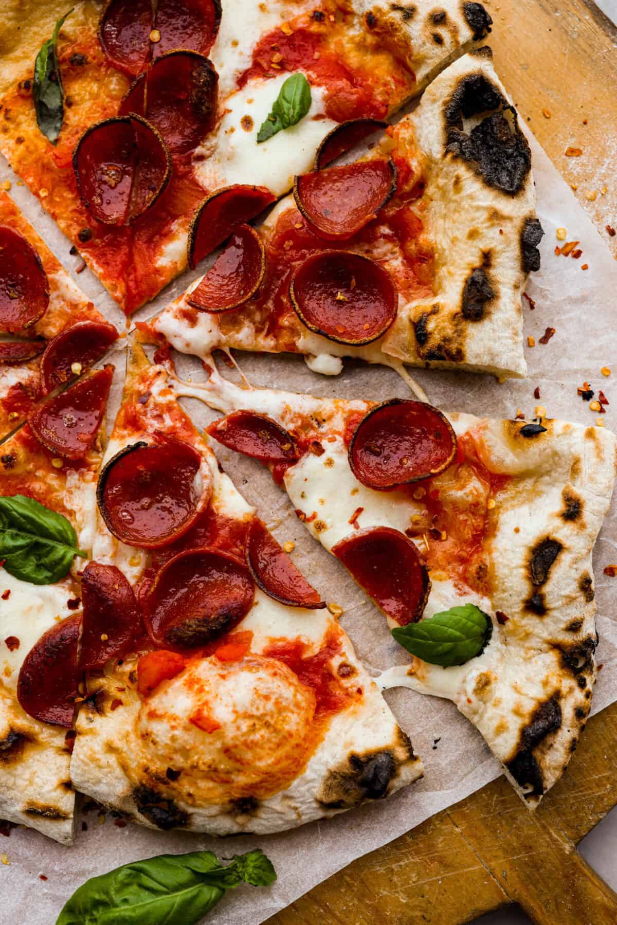 This is the perfect beginner's guide for making wood-fired pizza dough! Pizza expert, Chef Brandon Price, taught me how to make authentic homemade pizza, and now you get to learn too! Top view of wood-fired pizza cut into slices.