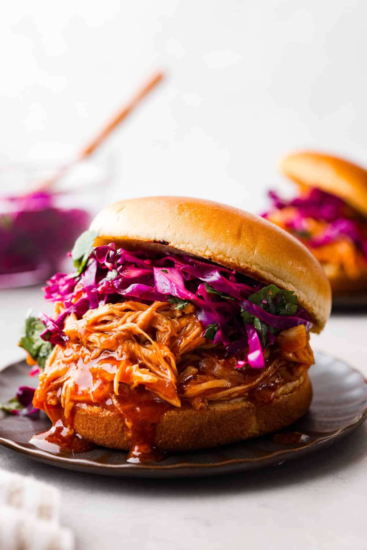 This Homemade BBQ Sauce recipe has the most amazing flavor combination and only takes minutes to make! It's sweet and tangy and has the perfect amount of smokiness that makes this BBQ sauce a family favorite! Close view of a pulled chicken sandwich slathered in bbq sauce and coleslaw.