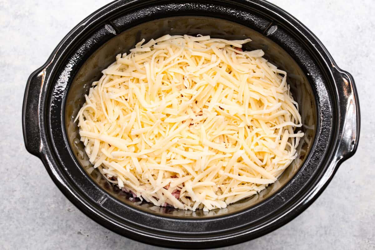 Treat yourself to this easy, Slow Cooker Chicken Cordon Bleu recipe! With tender chicken, savory ham, and melty Swiss cheese, it's a perfect comfort meal for any day. Cheese sprinkled on top of the chicken and ham.