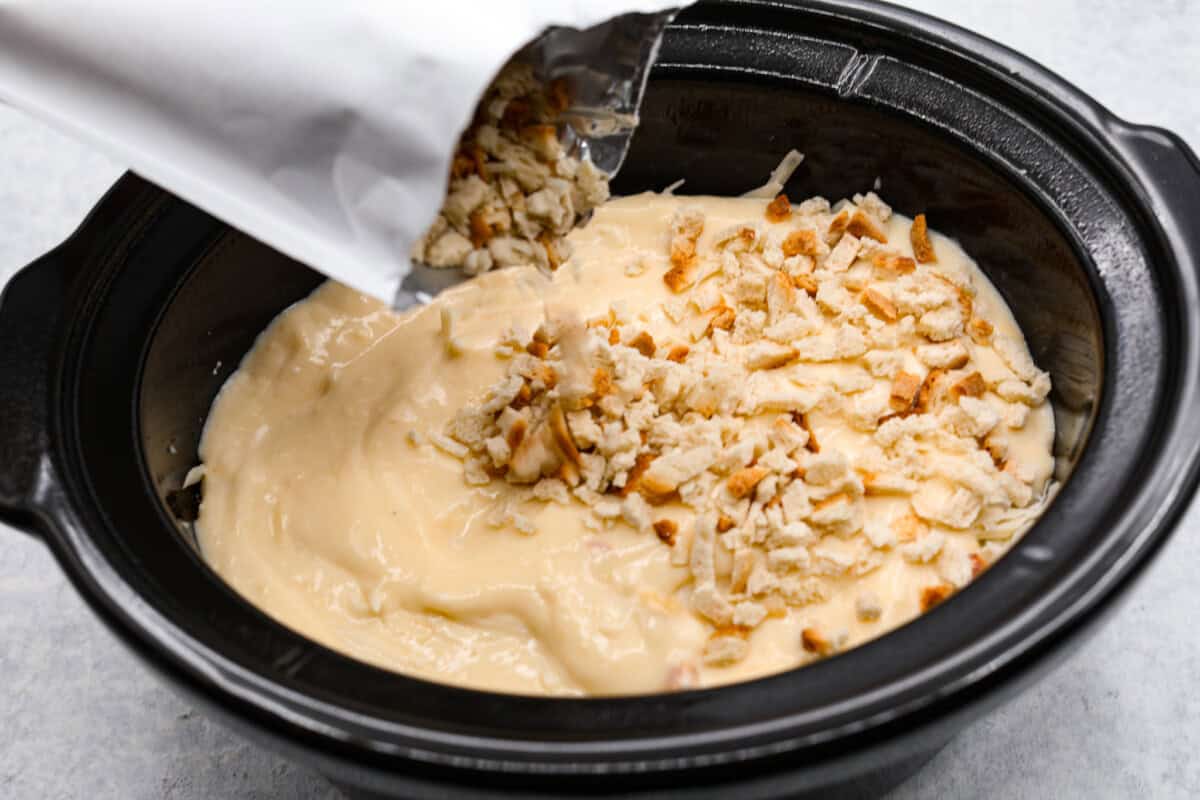 Treat yourself to this easy, Slow Cooker Chicken Cordon Bleu recipe! With tender chicken, savory ham, and melty Swiss cheese, it's a perfect comfort meal for any day. Stuffing being poured onto the slow cooker chicken cordon bleu.
