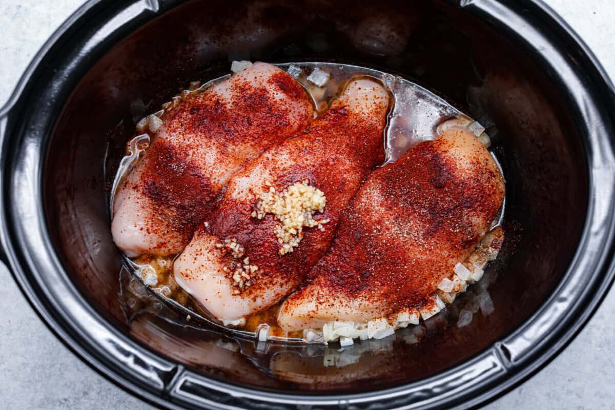 Honey lime chicken enchiladas are a family favorite! These enchiladas are filled with shredded chicken and melty cheese and then smothered in a creamy enchilada sauce. The combination of honey and lime takes these enchiladas to the next level! First photo of the chicken ingredients in the crockpot.