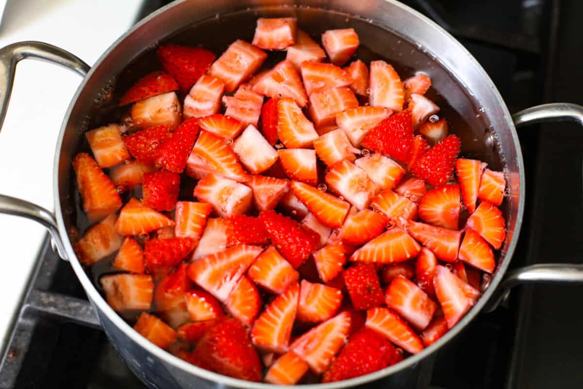 This strawberry pie filling recipe is perfect for anyone who loves a sweet and tangy treat. With easy-to-follow steps and simple ingredients, you'll have a quart of delicious filling ready to enjoy in no time. Strawberries being blanched in boiling water on the stove.
