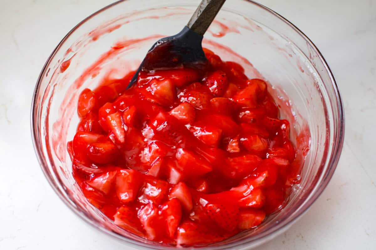 This strawberry pie filling recipe is perfect for anyone who loves a sweet and tangy treat. With easy-to-follow steps and simple ingredients, you'll have a quart of delicious filling ready to enjoy in no time. a bowl of strawberry mixture in a glass bowl.