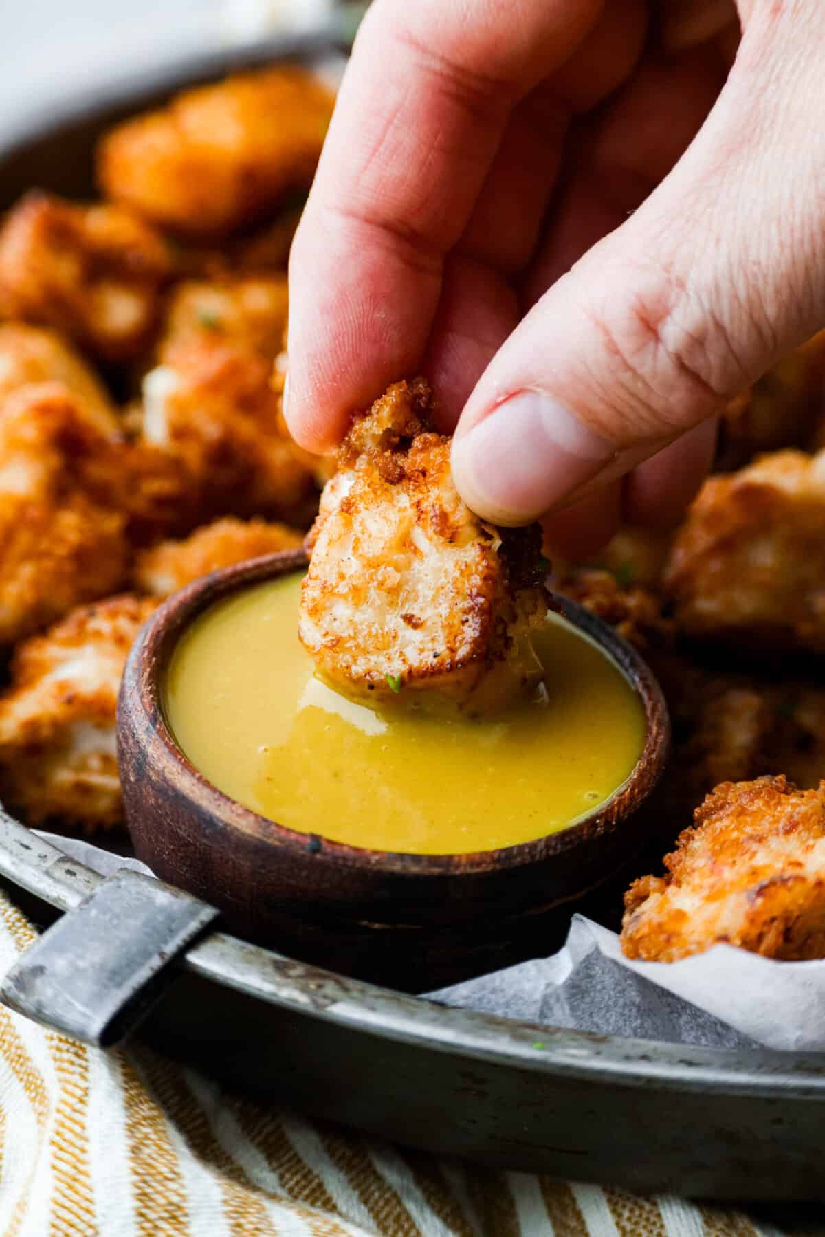 These Chick-fil-A Nuggets taste just like the real thing! They are crispy and salty with the slightest hint of sweetness.ย Pair them with the Chick-fil-A sauce and make the perfect family meal! A copycat Chick-fil-A nugget being dipped in homemade chick-fil-a sauce.