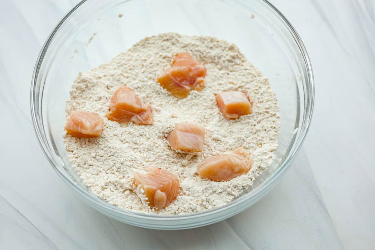 These Chick-fil-A Nuggets taste just like the real thing! They are crispy and salty with the slightest hint of sweetness.ย Pair them with the Chick-fil-A sauce and make the perfect family meal! Raw chicken being coated with the dry ingredients in a glass bowl.
