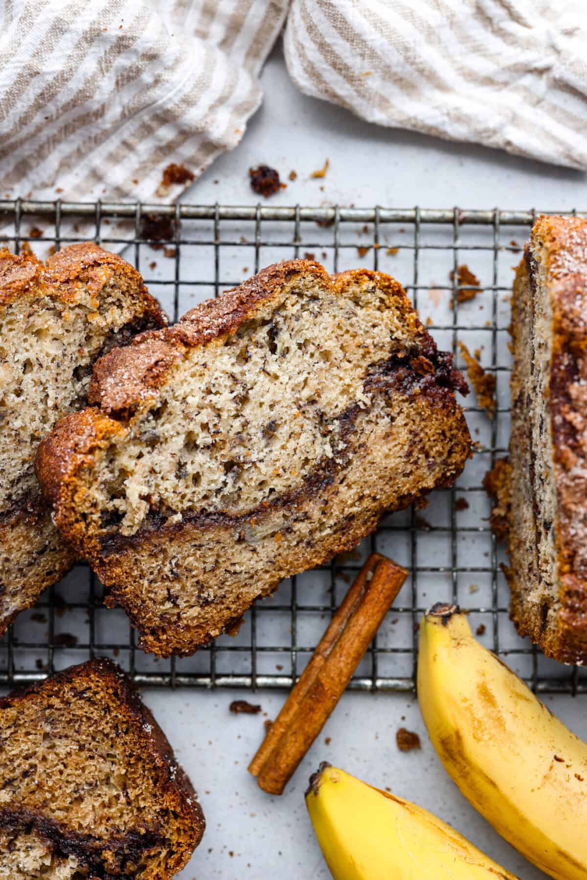 Cinnamon Swirl Banana Bread is a delightful twist on the classic. What sets this recipe apart is the luscious cinnamon sugar swirl running through the middle and on top, creating a beautiful marbled effect and an extra burst of flavor. It's irresistibly delicious! Overhead shot of a slice of cinnamon swirl banana bread on cooling rack.