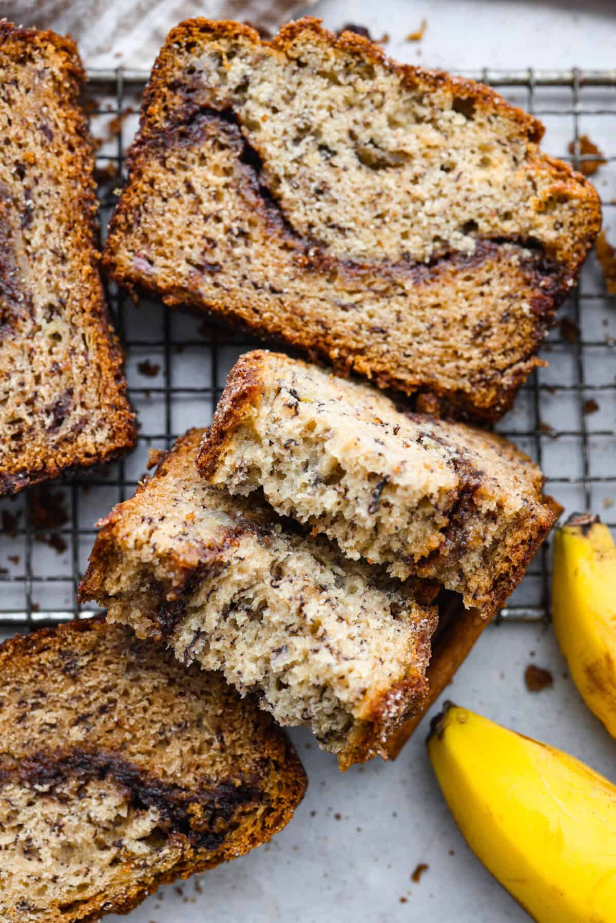 Cinnamon Swirl Banana Bread is a delightful twist on the classic. What sets this recipe apart is the luscious cinnamon sugar swirl running through the middle and on top, creating a beautiful marbled effect and an extra burst of flavor. It's irresistibly delicious! Close up shot of sliced banana bread.