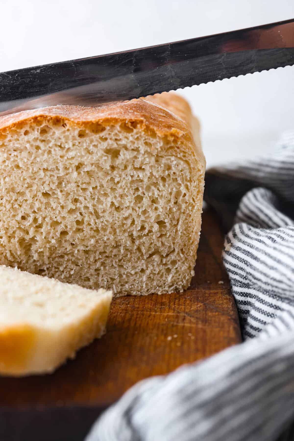 You want to make bread, but where do you start? My beginner's guide to baking bread is here to save the day! Feel confidentย at bread-making while I hold your hand through the whole process. Close view of a serrated knife slicing a loaf of bread.