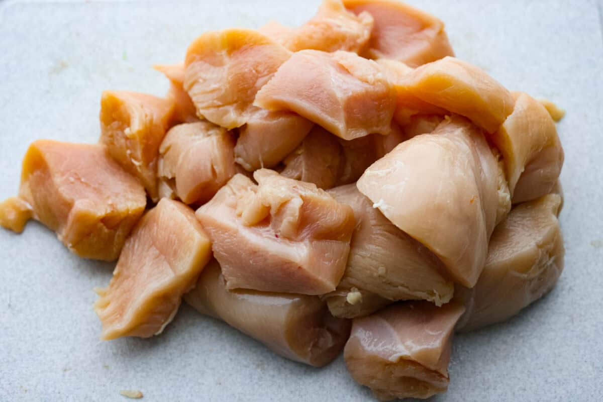 This sheet pan teriyaki chicken with vegetables is a family favorite! It's loaded with tender chicken and veggies that get tossed in a homemade teriyaki sauce. A one pan dinner recipe that is super easy to throw together. First photo of chicken cut into pieces.