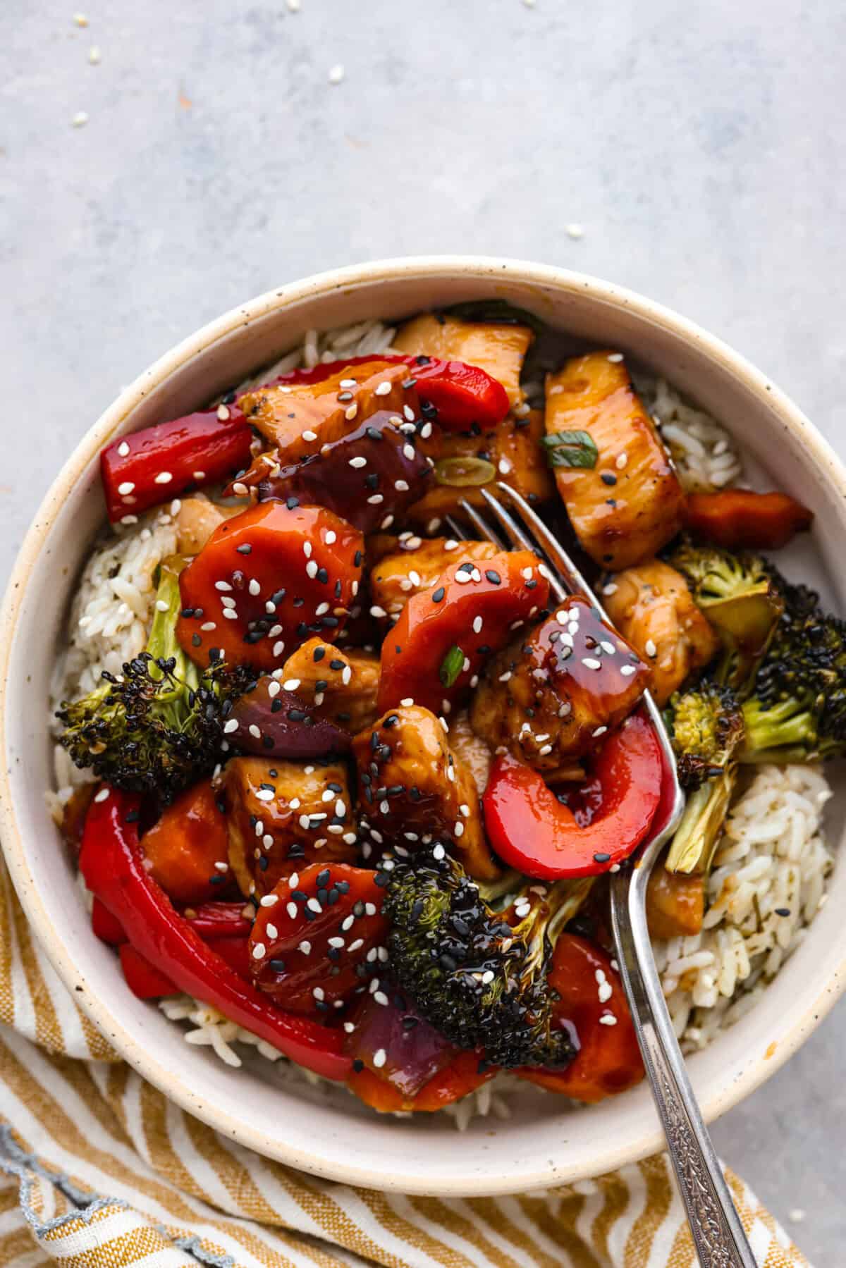 This sheet pan teriyaki chicken with vegetables is a family favorite! It's loaded with tender chicken and veggies that get tossed in a homemade teriyaki sauce. A one pan dinner recipe that is super easy to throw together. Top view of sheet pan teriyaki chicken and vegetables in a bowl over rice.