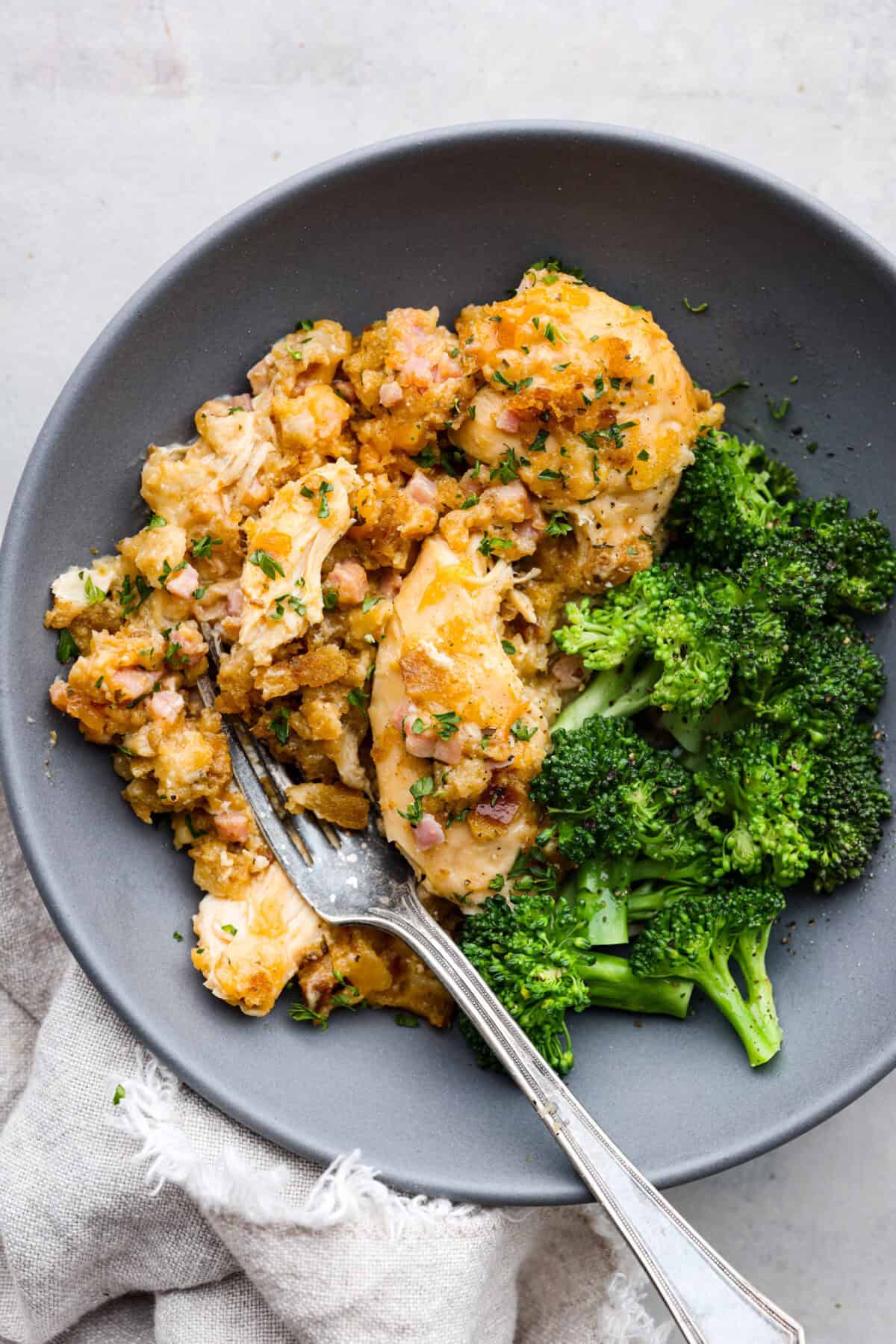 Treat yourself to this easy, Slow Cooker Chicken Cordon Bleu recipe! With tender chicken, savory ham, and melty Swiss cheese, it's a perfect comfort meal for any day. Slow cooker chicken cordon bleu on a plate with some broccoli.