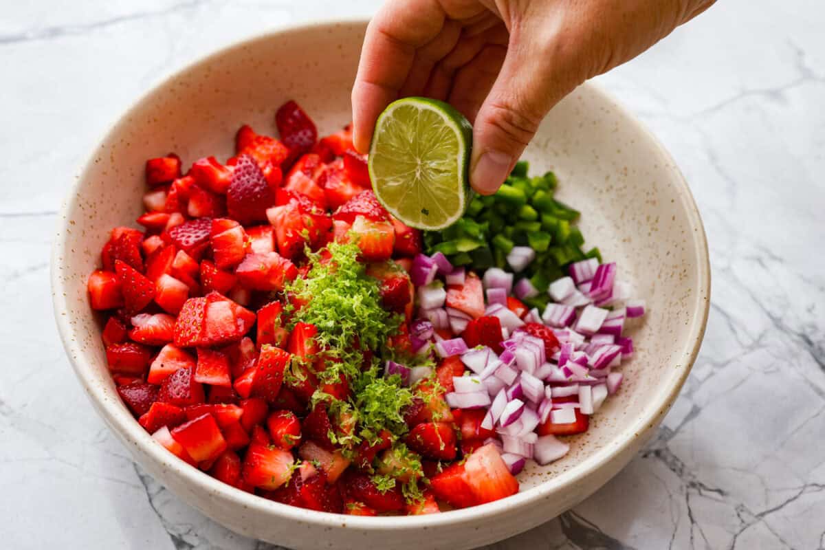 Add a burst of fresh, fruity flavor to your table with this Strawberry Salsa. This quick and easy recipe combines sweet strawberries with a hint of spice and is perfect for a light and refreshing snack in just 10 minutes! Lime being squeezed into the salsa.