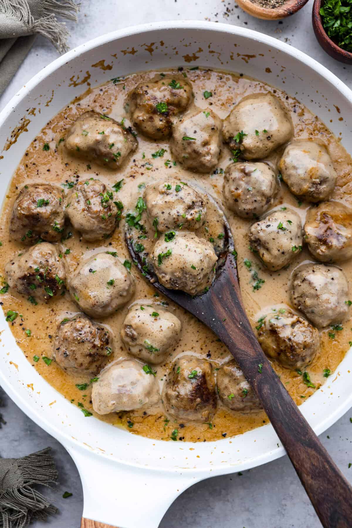 These areย a top favorite recipe on the siteย for a reasonโjuicy meatballs, rich creamy gravy, and SO MUCH FLAVOR. Theyโre easy to make andย way better than IKEAโsย (yes, really!). A pan filled with cooked Swedish Meatballs with a wooden spoon.