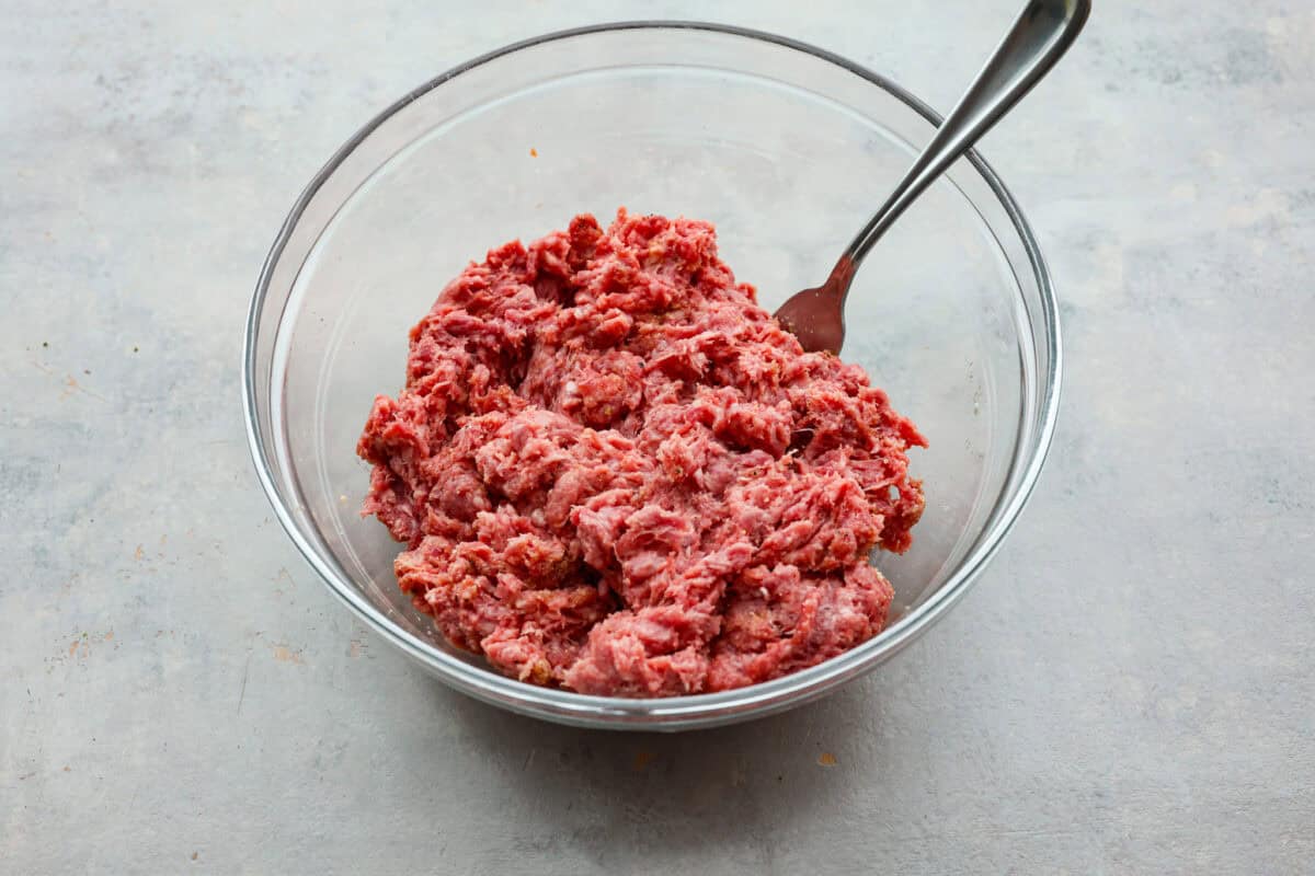Get ready for the ultimate burger experience topped with my irresistible Secret Sauce. The flavor packed into this burger is a delicious twist on a classic favorite. Ground beef mixed in a glass bowl.