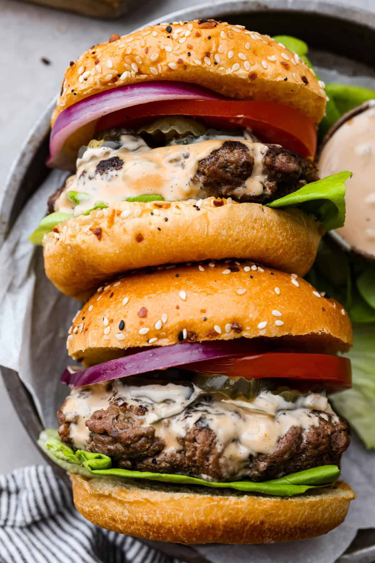 Get ready for the ultimate burger experience topped with my irresistible Secret Sauce. The flavor packed into this burger is a delicious twist on a classic favorite. 2 burgers laid on they side on a plate.