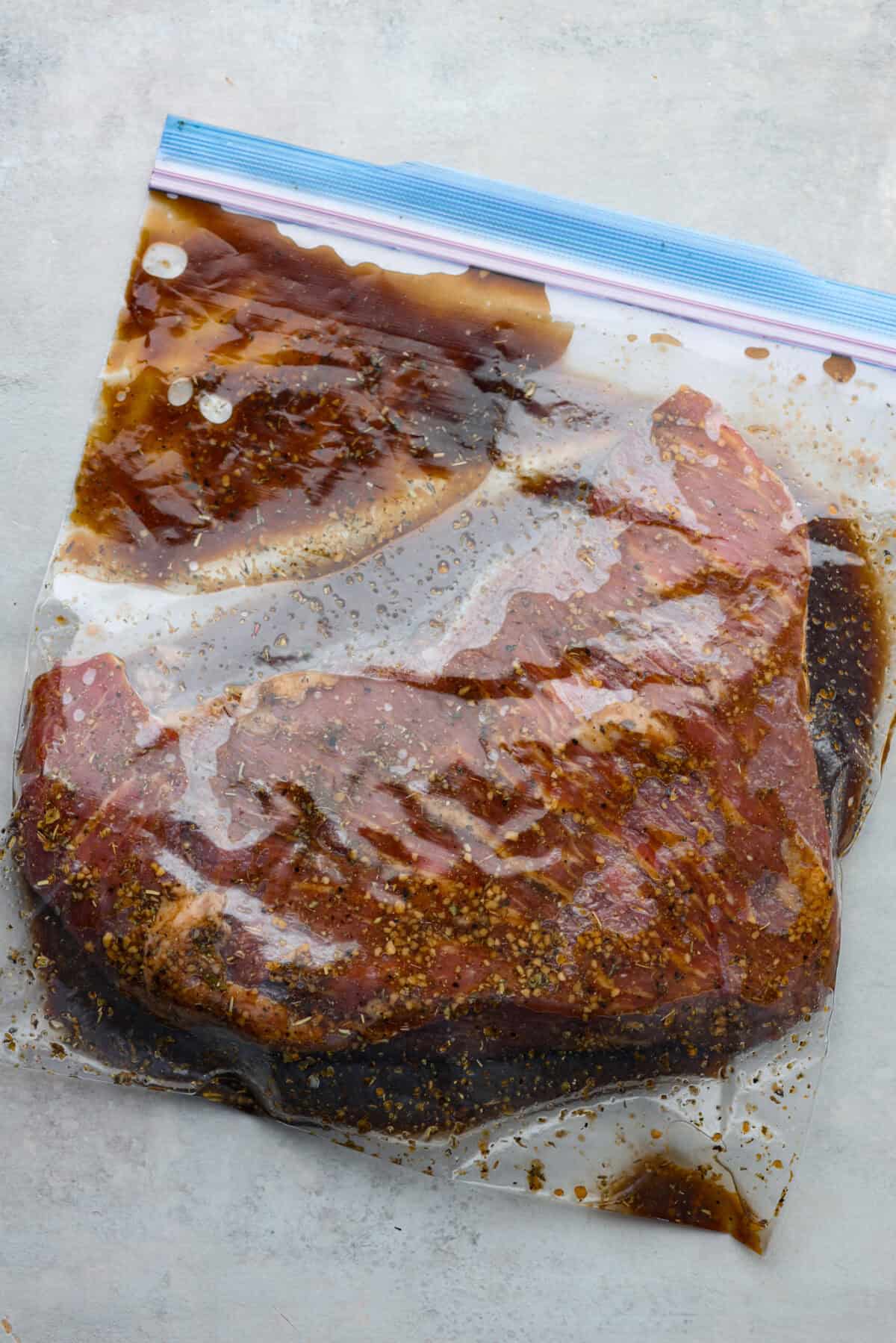 This tasty tri-tip marinade is the best way to infuse your tri-tip steak with delicious flavor and make it perfectly tender. It's easy to mix together with ingredients like soy sauce, brown sugar, fresh garlic and seasonings for the most wonderful savory, sweet, and tangy taste. Tri tip in a ziplock bag with marinade.