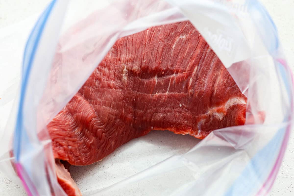 This tasty tri-tip marinade is the best way to infuse your tri-tip steak with delicious flavor and make it perfectly tender. It's easy to mix together with ingredients like soy sauce, brown sugar, fresh garlic and seasonings for the most wonderful savory, sweet, and tangy taste. Tri Tip in a ziplock bag.