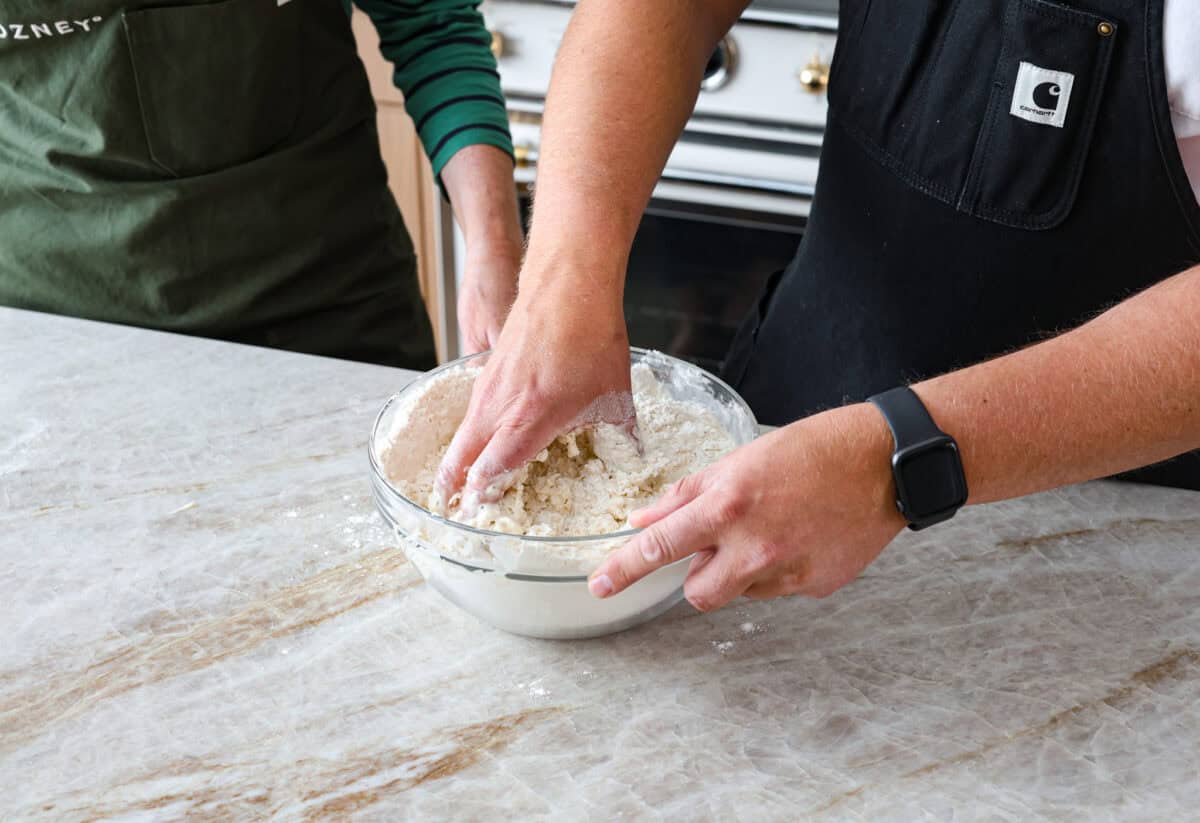 This is the perfect beginner's guide for making wood-fired pizza dough! Pizza expert, Chef Brandon Price, taught me how to make authentic homemade pizza, and now you get to learn too! Fourth photo of mixing the dough with hands.