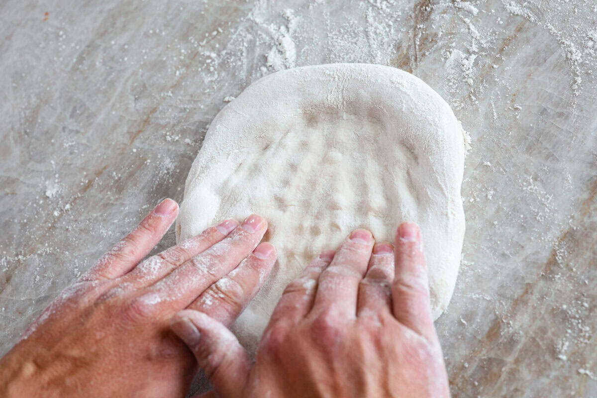 This is the perfect beginner's guide for making wood-fired pizza dough! Pizza expert, Chef Brandon Price, taught me how to make authentic homemade pizza, and now you get to learn too! Third photo of pressing the dough to create the pizza round.