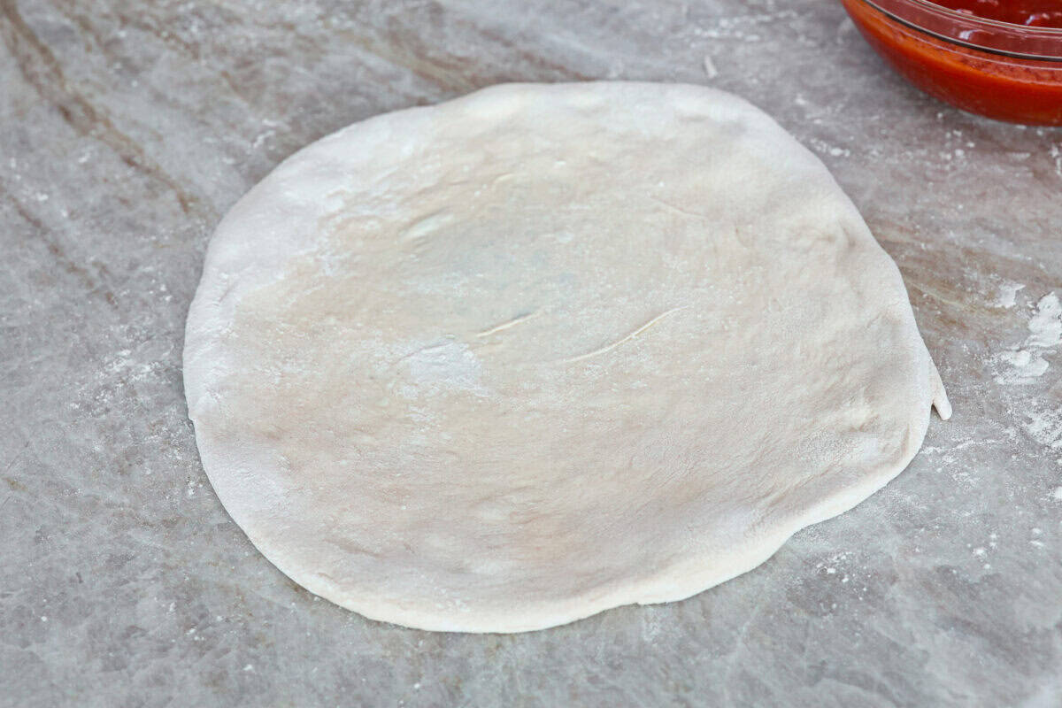 This is the perfect beginner's guide for making wood-fired pizza dough! Pizza expert, Chef Brandon Price, taught me how to make authentic homemade pizza, and now you get to learn too! Fourth photo of the finished 12" pizza round ready for toppings.