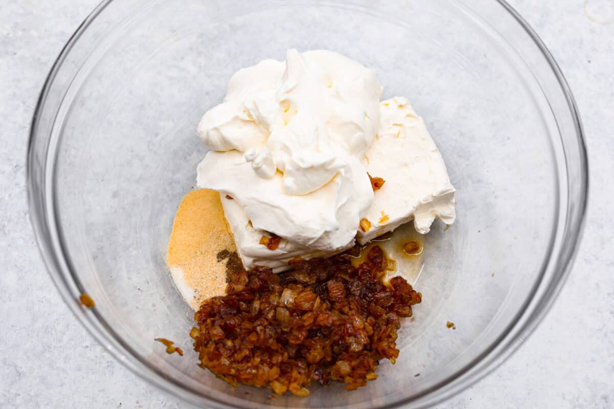 The Best French Onion Dip begins with caramelized onions that combine with cream cheese, sour cream, and seasonings. It creates a dip so addictive and creamy, it'll be gone before you know it! Third photo of dip ingredients in a large bowl.