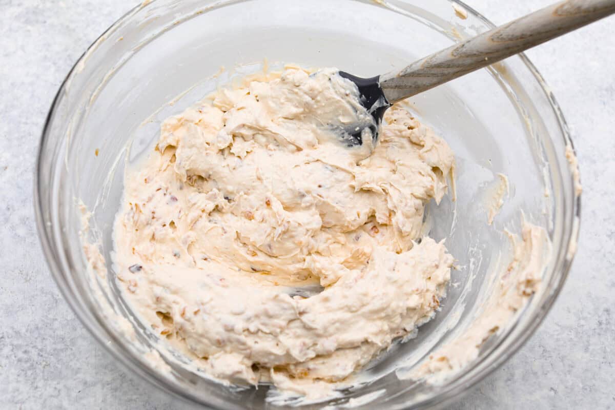 The Best French Onion Dip begins with caramelized onions that combine with cream cheese, sour cream, and seasonings. It creates a dip so addictive and creamy, it'll be gone before you know it! Fourth photo of the dip ingredients mixed together in a bowl.