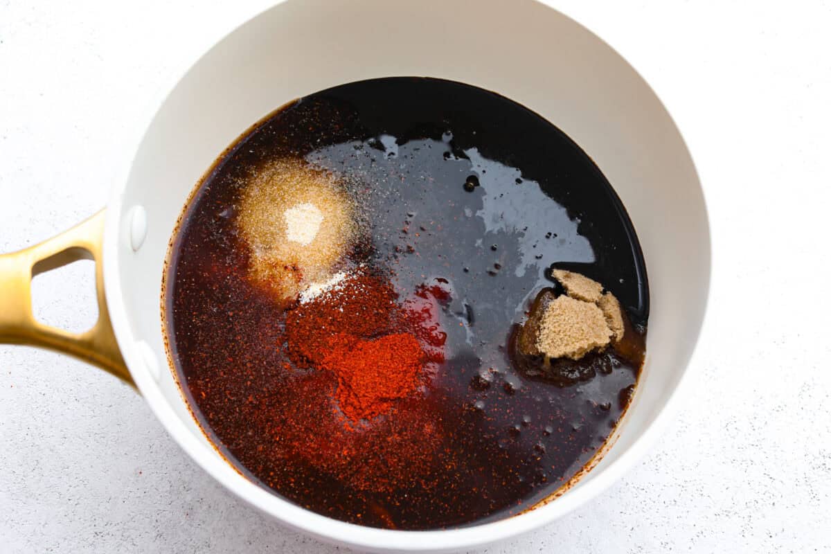 This Homemade BBQ Sauce recipe has the most amazing flavor combination and only takes minutes to make! It's sweet and tangy and has the perfect amount of smokiness that makes this BBQ sauce a family favorite! First photo of the bbq sauce ingredients added to a saucepan.