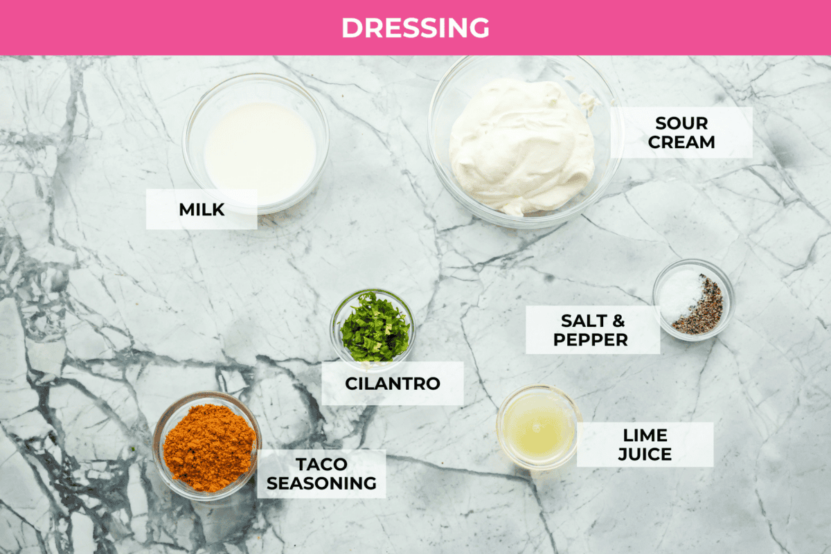 Beef taco salad is a delicious and simple family favorite, perfect for summer evenings! Packed with your favorite taco essentials like beans, corn, avocado, and fresh cilantro, it's bursting with flavor and sure to become a staple dish! Overhead shot of labeled ingredients for taco salad dressing.