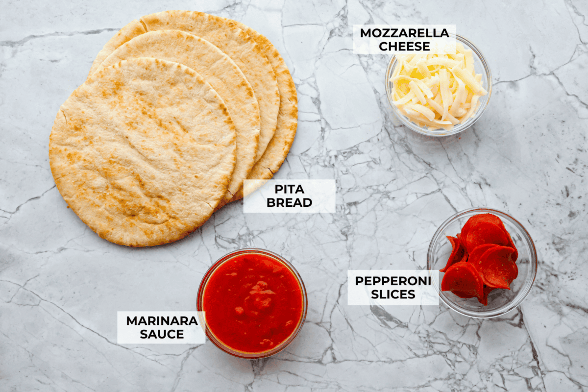 Pita pizza is like having your own personalized mini-pizza! Grab some ready-made pitas, pile on your favorite toppings, and indulge in a quick and tasty snack for a delightful way to satisfy your pizza craving whenever it strikes! Overhead shot of labeled ingredients.