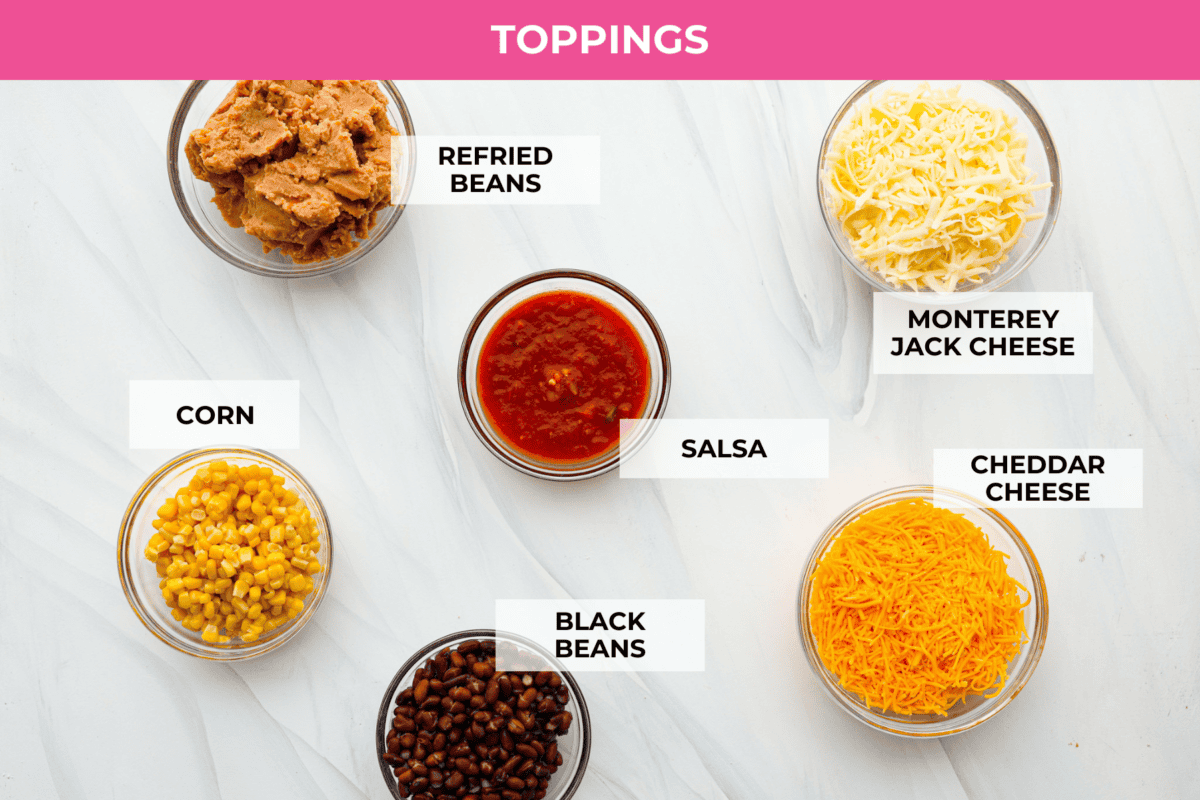 Tater Tot Nachos (Totchos) are made with crispy golden tater tots, topped with seasoned beef, scoops of refried beans, corn, black beans, salsa and melty cheese. Add your favorite toppings and dig in! Overhead shot of topping ingredients labeled.