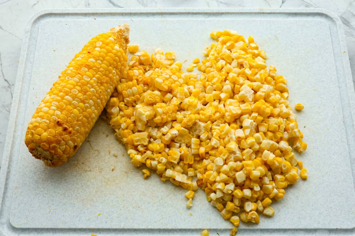 This Italian Corn Salad is bursting with fresh flavors from sweet corn, juicy grape tomatoes, crisp green bell pepper, and sharp parmesan cheese. Tossed in a zesty homemade Italian dressing, it’s perfect for summer or any time of the year. Overhead shot of corn cut off from a corn on the cob.