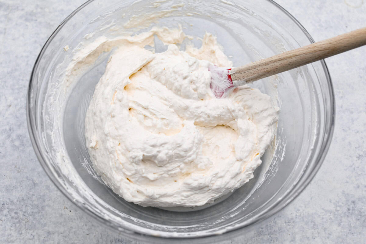 This strawberry cream cheese pie has a smooth, creamy filling is topped with sweet strawberries and is held together by a crumbly, buttery crust. Simply divine! Overhead shot of whipped topping and cream cheese mixed in a bowl.